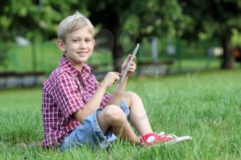 happy boy play with tablet pc in park