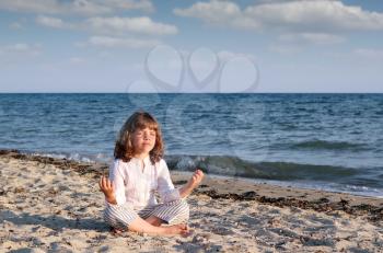 little girl meditating on the beach
