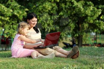 child and girl with laptop in park
