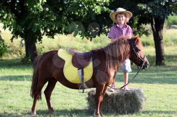 happy boy with pony horse on field