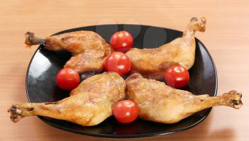 chicken drumstick and tomatoes on black dish