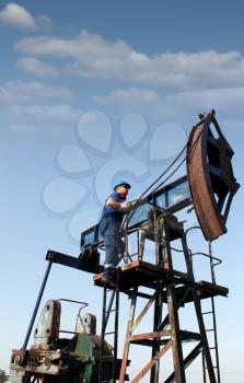 oil worker climbs up to the pump jack