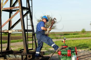 worker with pipe wrench on oilfield pipeline