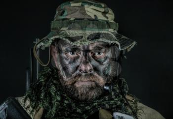 Special forces United States in Camouflage Uniforms studio shot. Wearing jungle hat, Shemagh scarf, painted face. Black background
