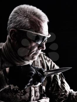 Close up studio shot of special forces white-haired veteran with knife