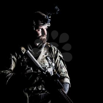 Studio contour backlight shot of special forces soldier in uniforms with weapons, portrait on black background