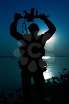 Army soldier with rifle above his head night moon silhouette. Victory concept