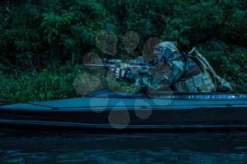 Special forces man with painted face in camouflage uniforms in army kayak. Seeking target, diversionary mission, twilight