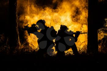 Backlit silhouette of special forces marine operators in forest on fire explosion background. Battle, bombs exploding, they fighting no matter what