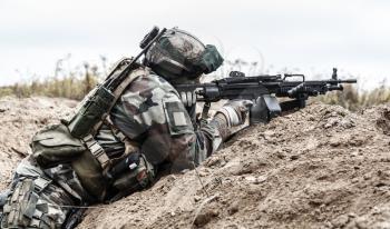 Machine gunner of 1st Marine Infantry Parachute Regiment RPIMA firing from defensive position trench, profile side view