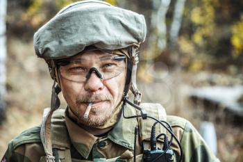 Norwegian Armed Forces Special Command FSK soldier smoking cigarette closeup portrait. Radio and headset are on