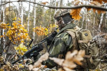 Norwegian Rapid reaction special forces FSK soldier patrolling in the forest. Field camo uniforms, combat helmet and eye-wear goggles are on