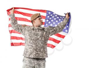 Army Ranger from Special Troops Battalion in universal Camouflage pattern Uniforms and Tan beret with Ranger Regiment crest standing and holding waving US flag in his hands proudly. National holidays: Veterans Day, Memorial Day
