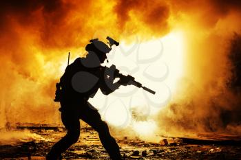 Black silhouettes of soldier in the smoke fire burning moving in battle operation. Back light