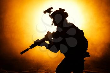 Black silhouettes of soldier in the smoke fire burning moving in battle operation. Back light