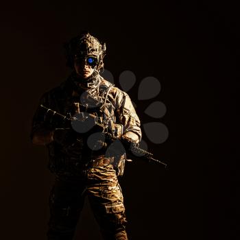 Elite member of US Army rangers in combat helmet and night vision device. Studio shot, dark black background, looking at camera, dark contrast