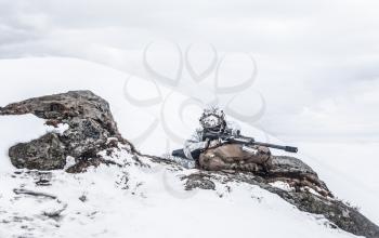 Army soldier with Sniper rifle in action in the Arctic. He lies among the cold rocks and stones, almost freezing to death, but waiting as long as enemies appear to kill them. Duty, service and loyalty