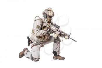 Army soldier in Protective Combat Uniform holding Special Operations Forces Combat Assault Rifle. Shooting weapon in kneeling position. Studio shot, isolated on white background