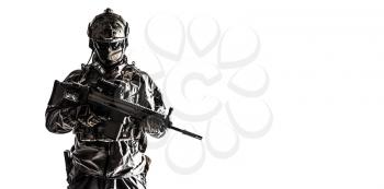Army soldier in Protective Combat Uniform holding Special Operations Forces Combat Assault Rifle. Studio shot, dark contrast, cropped, desaturated, isolated on white background