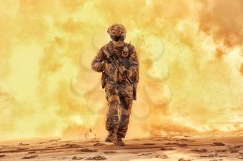 Army soldier in military camouflage uniform, helmet, with face hiding behind mask and glasses, running out from fire. Infantry rush with fire support, commando attack and breakthrough on battlefield