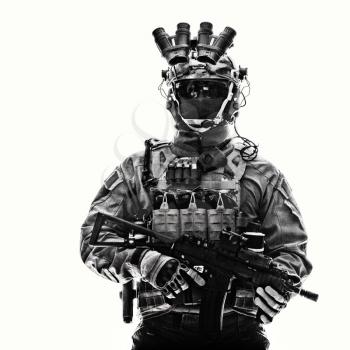 Half length studio portrait of anti-terrorist squad fighter, special operations soldier, military company mercenary in tactical ammunition with night vision device, armed short barrel assault rifle