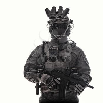 Half length studio portrait of anti-terrorist squad fighter, special operations soldier, military company mercenary in tactical ammunition with night vision device, armed short barrel assault rifle