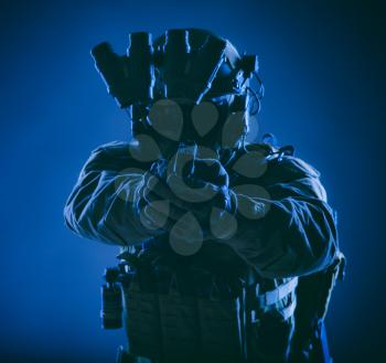 Modern infantry soldier, special forces fighter, police SWAT officer in helmet and body armor, equipped night vision device, aiming with service pistol in camera, front view, low key studio shoot