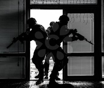 Police special anti-narcotics or counter-terrorism forces tactical team breaching door and entering in building during search and arrest warrant or hostage rescue operation, desaturated, high contrast