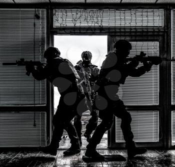 Police special anti-narcotics or counter-terrorism forces tactical team breaching door and entering in building during search and arrest warrant or hostage rescue operation, desaturated, high contrast