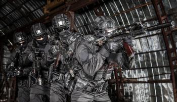 Police special operations emergency response team fighters in black uniforms, moving in stack formation behind squad leader who aiming with silenced assault rifle in close quarters combat conditions