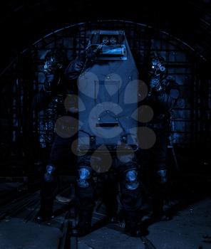 Police counter-terrorism, anti-narcotics forces tactical group, SWAT team hiding behind ballistic shield, aiming with weapons and trying reflect gunfire during hostage rescue, close quarters situation
