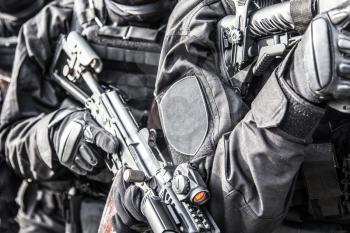 Police special operations tactical unit, SWAT members in black uniform armed with service rifles standing in stack formation during armed warrant, suspect arrest operation, cropped over shoulder view
