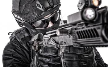 Close up portrait of police tactical team fighter, SWAT officer in black uniform, helmet, hidden behind mask and glasses face, aiming with assault rifle, studio shoot, isolated on white background