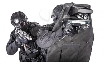 Two fighters of police quick reaction team, SWAT members, security company shooters aiming with pistol and assault rifle while hiding behind ballistic shield, studio shoot isolated on white background