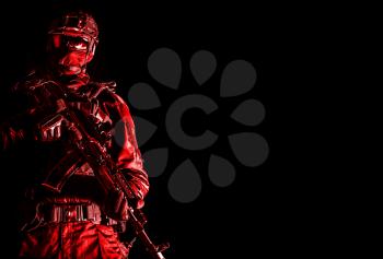 Police special forces, quick reaction team officer, tactical group fighter in black uniforms, helmet and hidden behind mask identity, armed with assault rifle, low key studio shoot on black background