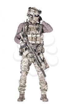 Strikeball enthusiast in checkered shirt wearing military ammunition, face mask, helmet and radio headset, tactical glasses, camo pants, armed service rifle and handgun studio shoot isolated on white