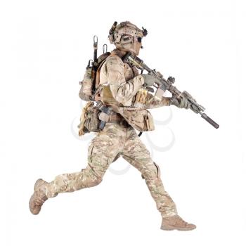 Army soldier, equipped infantryman, airsoft player in camouflage battle uniform, helmet and tactical radio headset jumping, running with assault rifle in hand studio shoot isolated on white background