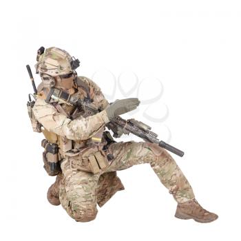 Special forces sergeant, battle squad leader in camo uniform, helmet with radio headset, armed rifle standing on knee, pointing direction, giving orders to teammates studio shoot isolated on white