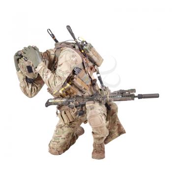 Armed infantryman in camo uniform and helmet embracing head with hands, covering himself from grenade, mine or air bomb explosion, artillery strike danger studio shoot isolated on white background