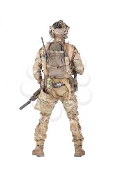 Army soldier in camo uniform and battle helmet, equipped tactical radio station with headset, wearing backpack, carrying ammo, rope, grenades in waist pouch, standing backwards isolated studio shoot