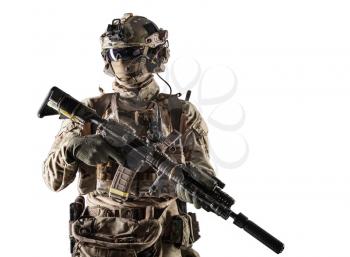 Special forces fighter in battle uniform and helmet with radio headset, face mask and ballistic glasses, standing with equipped laser sight and silencer service rifle studio portrait isolated on white