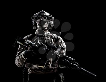 Modern army special forces equipped soldier, anti terrorist squad fighter, elite mercenary armed assault rifle, standing in darkness with night vision goggles on helmet, studio portrait, copyspace