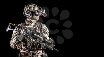 Half length portrait of army special forces rifleman, commando elite soldier equipped radio tactical headset, armed service rifle, using night vision goggles in darkness, isolated on black, copyspace