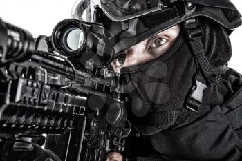 Close up studio portrait of police quick response group shooter in black uniform, searching target to shoot, observing area, aiming service rifle with optical sight close up portrait isolated on white