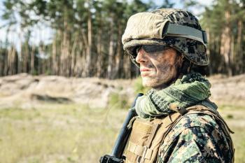 Location shot of United States Marine with rifle weapons in uniforms. Military equipment, army helmet, warpaint, smoked dirty face, tactical gloves. Weapons, army, american pride, patriotism concept