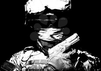 Special operations forces soldier in combat helmet with hidden behind balaclava and dark glasses face posing with sidearm service pistol in hand. Brown tone, high contrast, cropped on black background