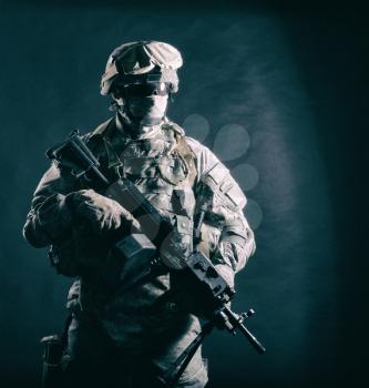 United States Marine Corps ranger, special forces soldier, security serviceman in battle uniform, armed with machine gun hiding his face with balaclava and glasses studio shot on black background