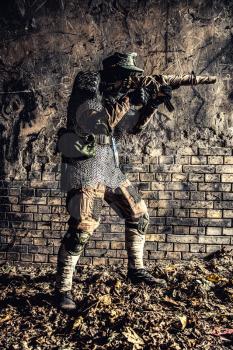 Post apocalyptic survivor, World War III soldier, global nuclear conflict partisan or stalker, in military cap and handmade body armor shooting with submachine gun wrapped in abandoned bunker or mine