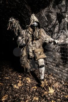 Post apocalyptic survivor, mysterious underground creature, stalker in gas mask and rags with runes, armed with handmade gun, hiding in dungeon, abandoned tunnel or city dark catacombs, sepia toned