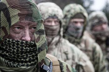 Army elite forces tactical group soldiers, skilled commandos squad, members wearing camouflage uniform, hiding faces behind masks, standing in line behind commander
